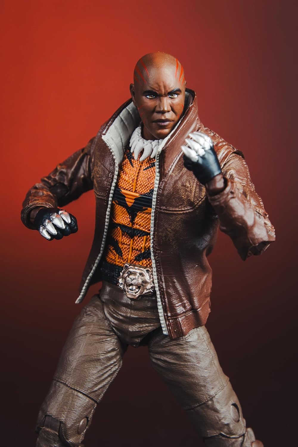 Acercamiento al torso de Bronze Tiger con el suéter de tigre naranja y la hebilla de cabeza de tigre